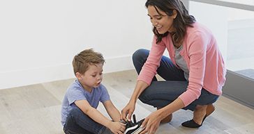 mom helping son tie his shoe